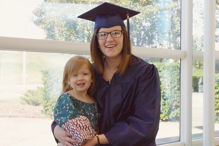 Father graduating, holding daughter in his arms